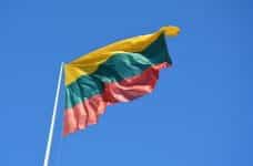 The flag of Lithuania against a blue sky.