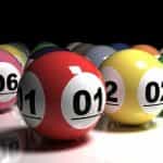 A collection of different colored lottery balls with different numbers on them placed carefully beside one another on a white table surface.