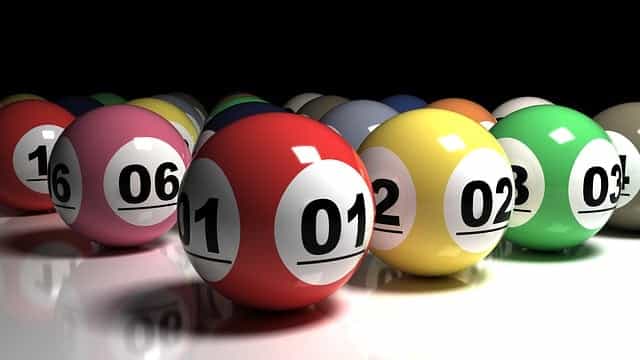 Kumpulan bola lotre berwarna berbeda dengan nomor berbeda ditempatkan dengan hati-hati di samping satu sama lain di atas permukaan meja putih.