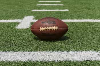A classic American football sitting on an outdoor football pitch at the start of a game.