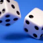 Two white dice spin in front of a blue surface.