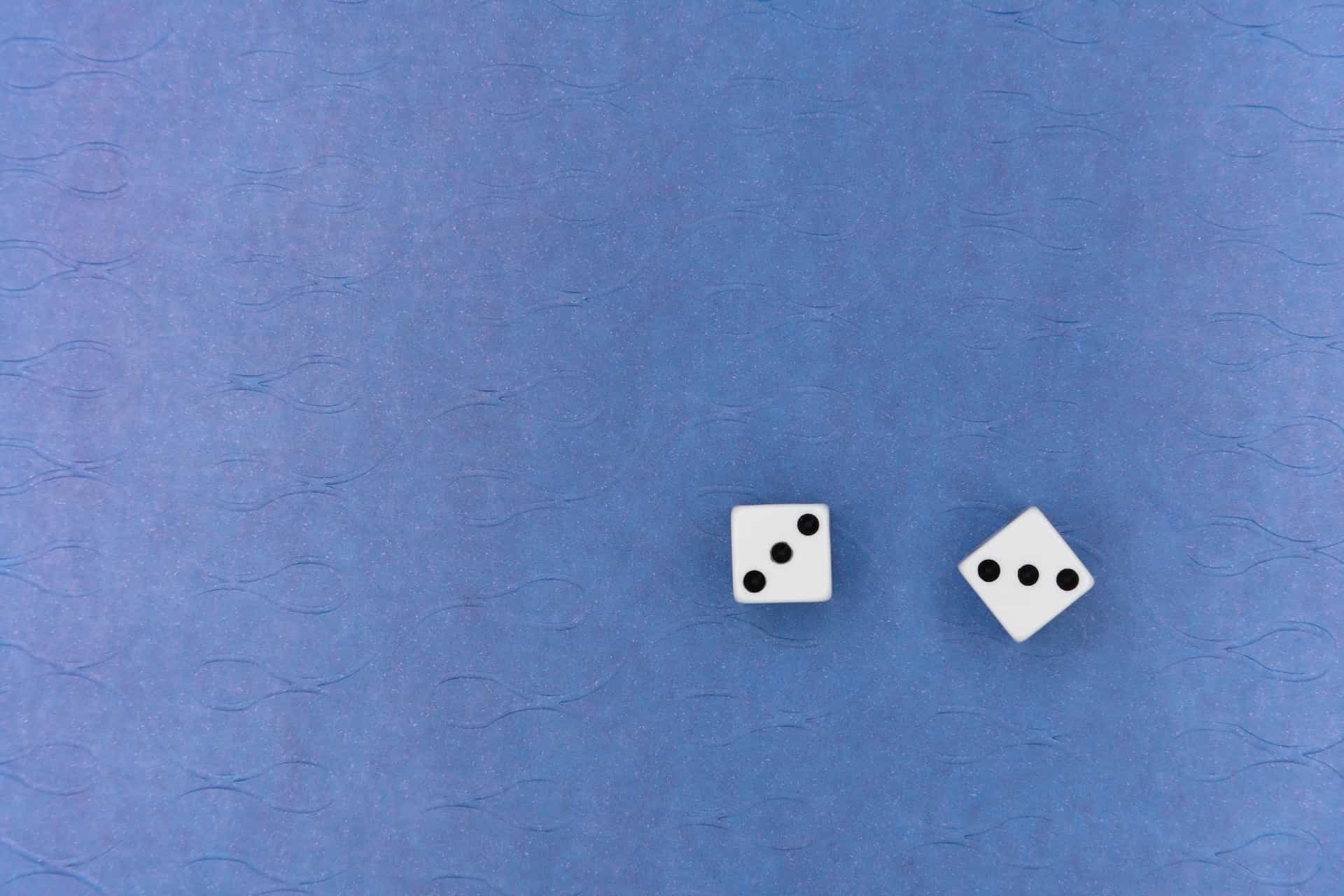 Dua dadu putih kecil di permukaan biru.