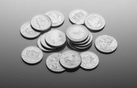 A collection of silver coins of different currencies lying on a table, some showing heads and other tails, with some stacked on top of one another while others lay around alone.