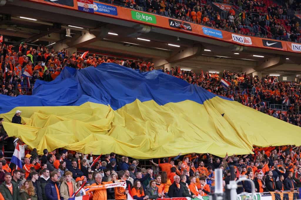 Fans mengibarkan bendera besar Ukraina selama pertandingan persahabatan internasional di Amsterdam, 2022.