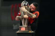 Michael Smith clutches the PDC World Darts Championship trophy he won in 2023.