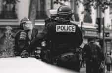 Black and white image of police in protective gear waiting at an event in Lyon, France.