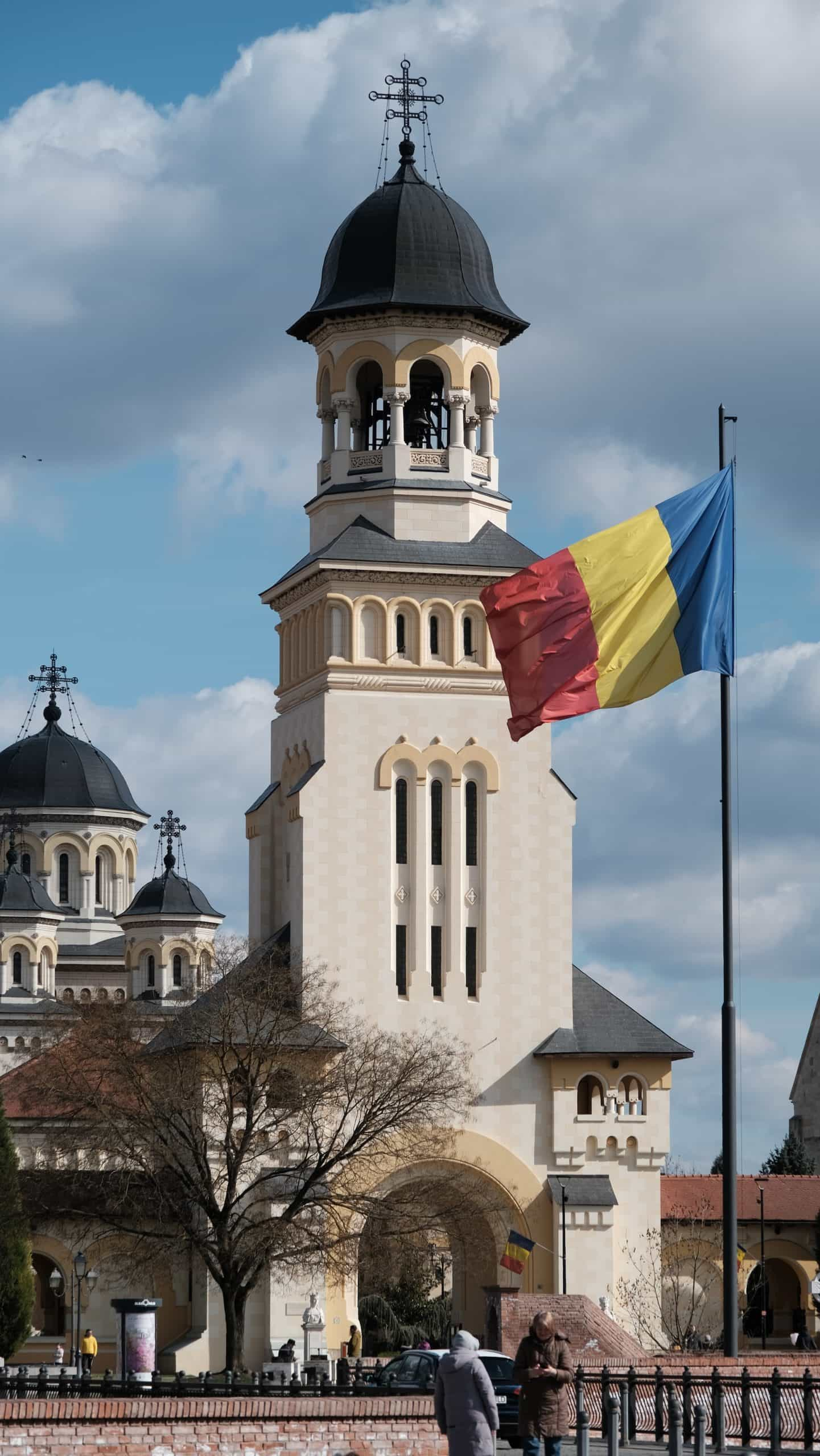 A flag flying in front of a building with a clock tower.