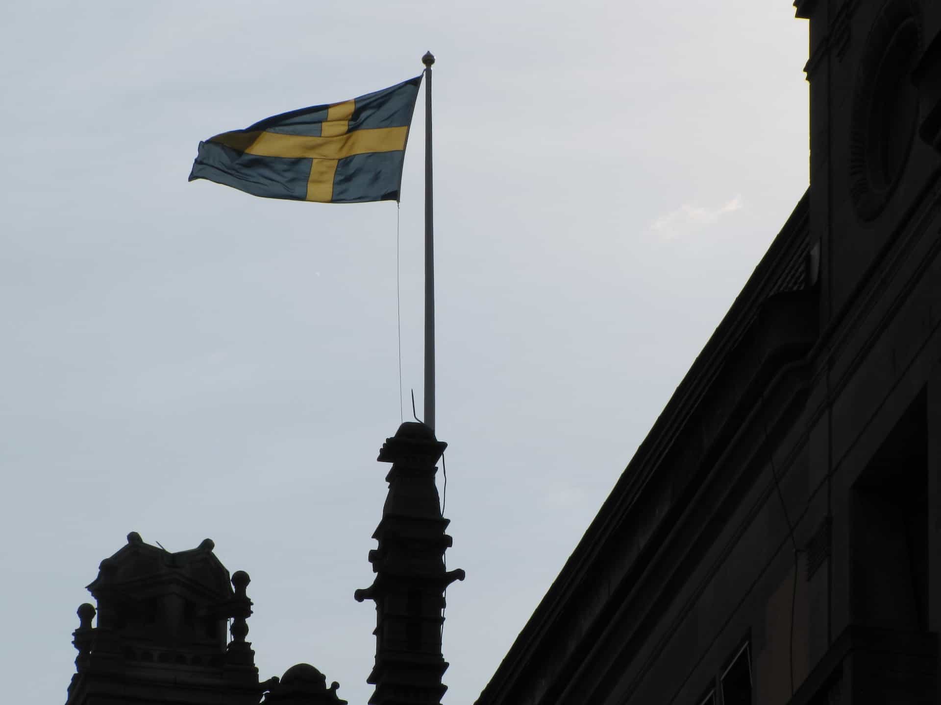 Sebuah bendera dikibarkan di atas sebuah bangunan di langit biru.