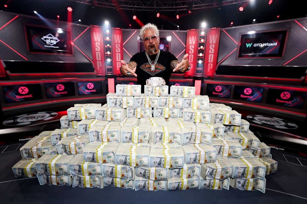 Guy Fieri Berpose dengan Gelang Acara Utama Poker Seri Dunia 2023 dan Setumpuk Uang Tunai di Horseshoe Las Vegas.