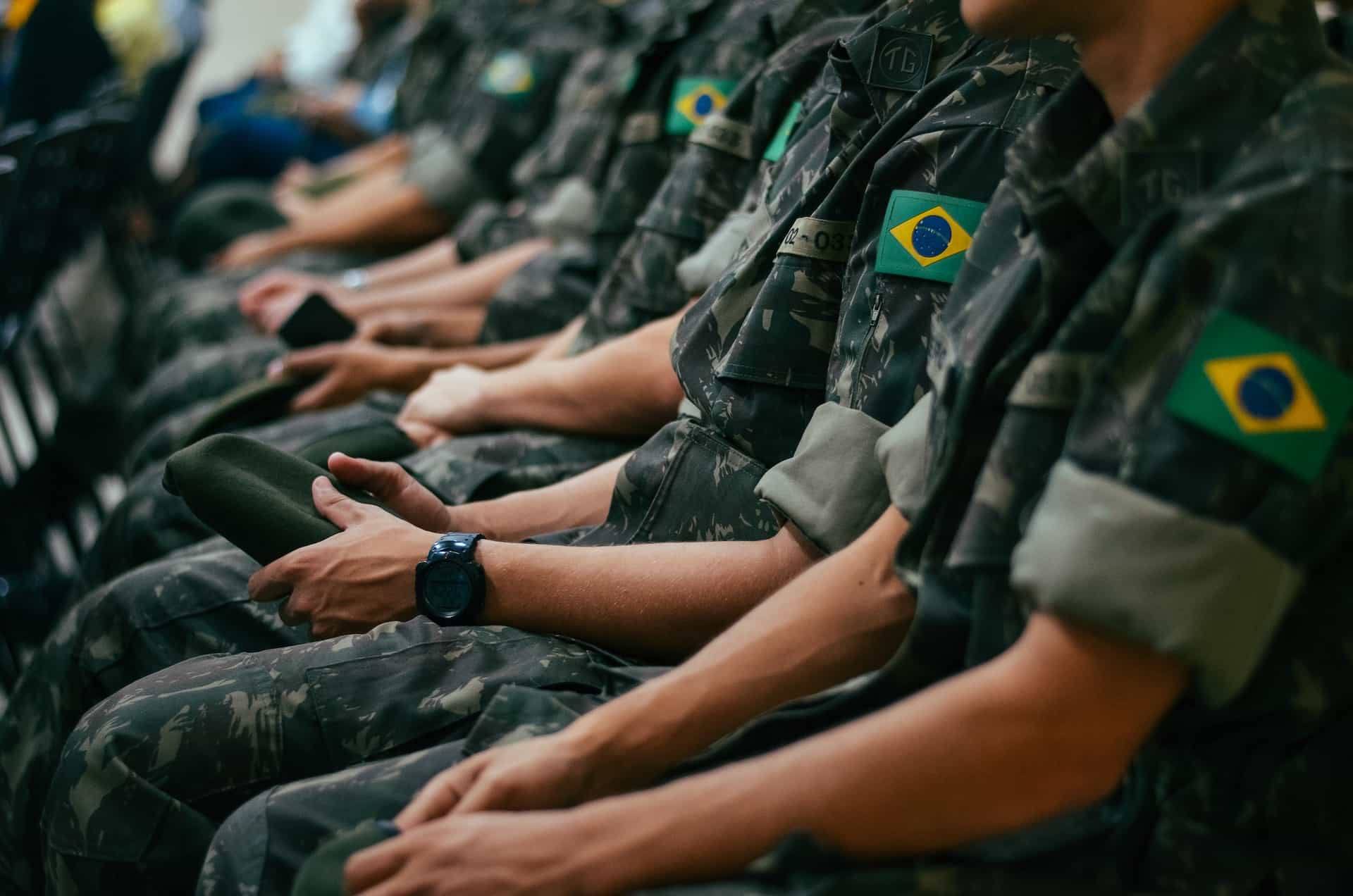 Army workers sit with the Brazilian flag on armbands of their camo uniforms.