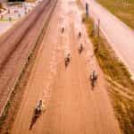 A group of horse-cart riders on a track.