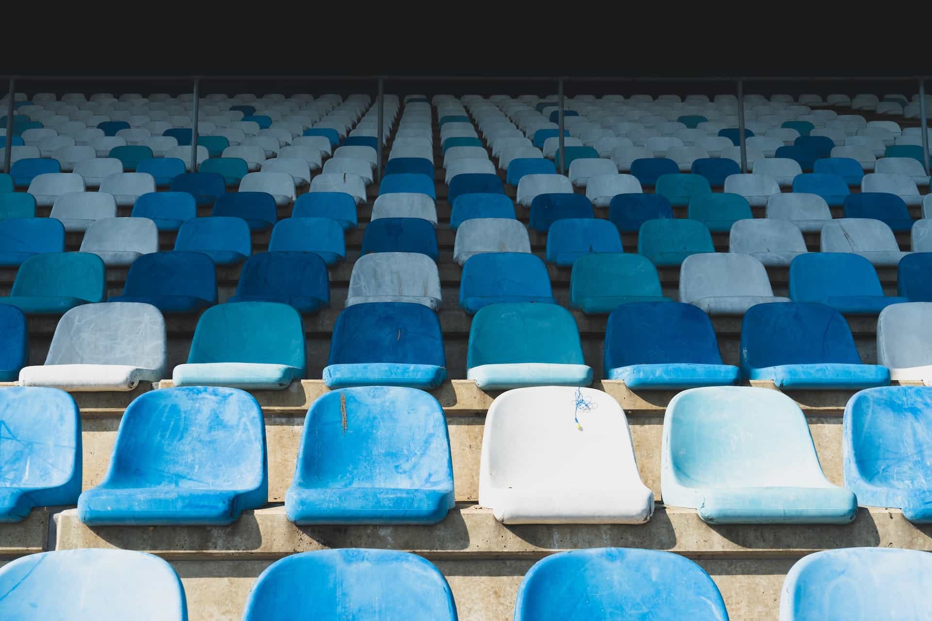 Empty blue plastic seats in a sporting grandstand.
