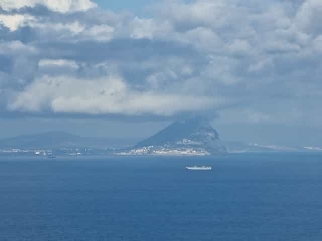 A cloudy ocean shore from the sea reveals the Rock of Gibraltar.