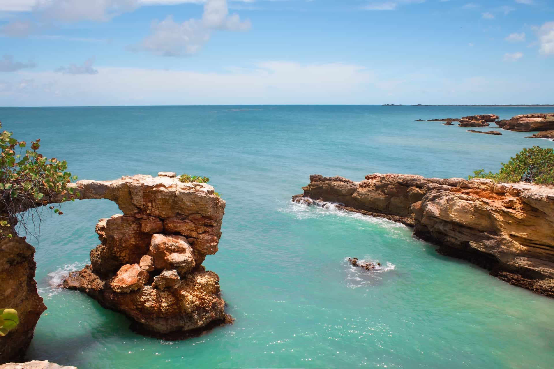 A formation of rocks and cliffs over bright blue water on Puerto Rico’s shore.