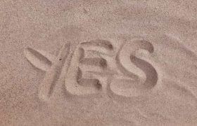 The word “yes” drawn into the sand on a beach or in a desert.