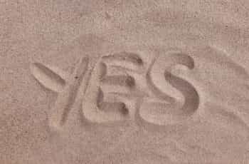 The word “yes” drawn into the sand on a beach or in a desert.