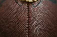 A very close up shot of an American football, featuring its iconic ridge and pigskin brown texture.