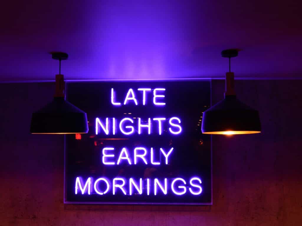 A neon sign above a bar reads LATE NIGHTS EARLY MORNINGS.