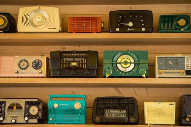 Rows of colorful retro radios sit on wood shelves.