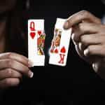 Playing cards, a Queen and King of Hearts, are torn in two.