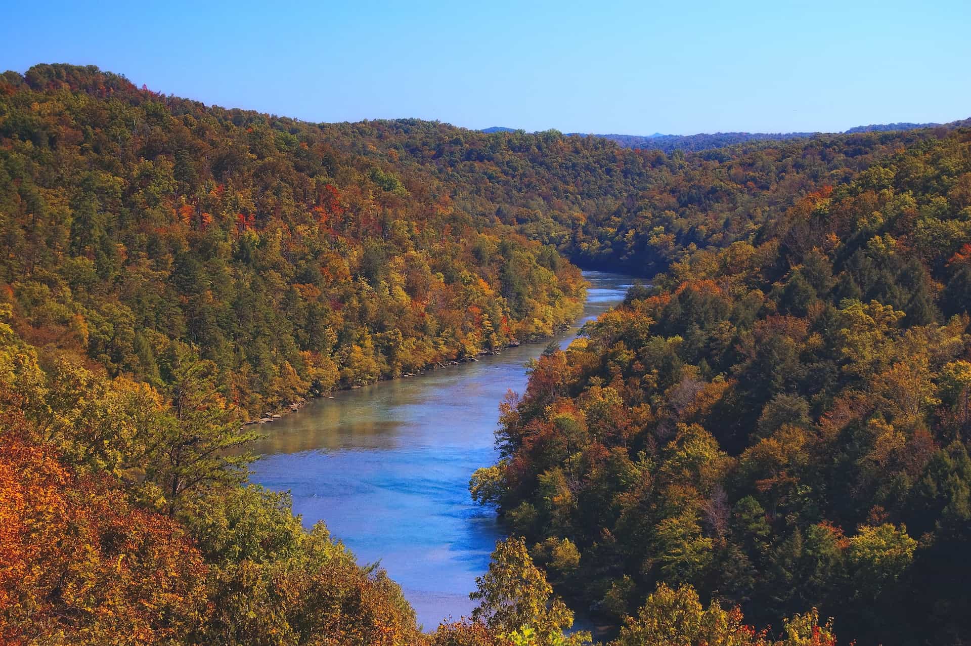 A scenic valley in rural Kentucky, featuring rolling forests changing color in the Fall, as well as a wide river cutting through the valley.