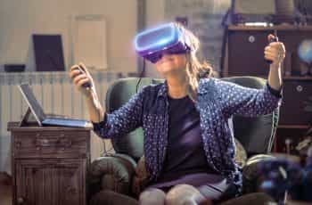 A smiling woman trying a virtual reality headset.
