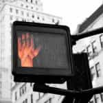 A traffic crossing illuminates a red hand to indicate stopping.