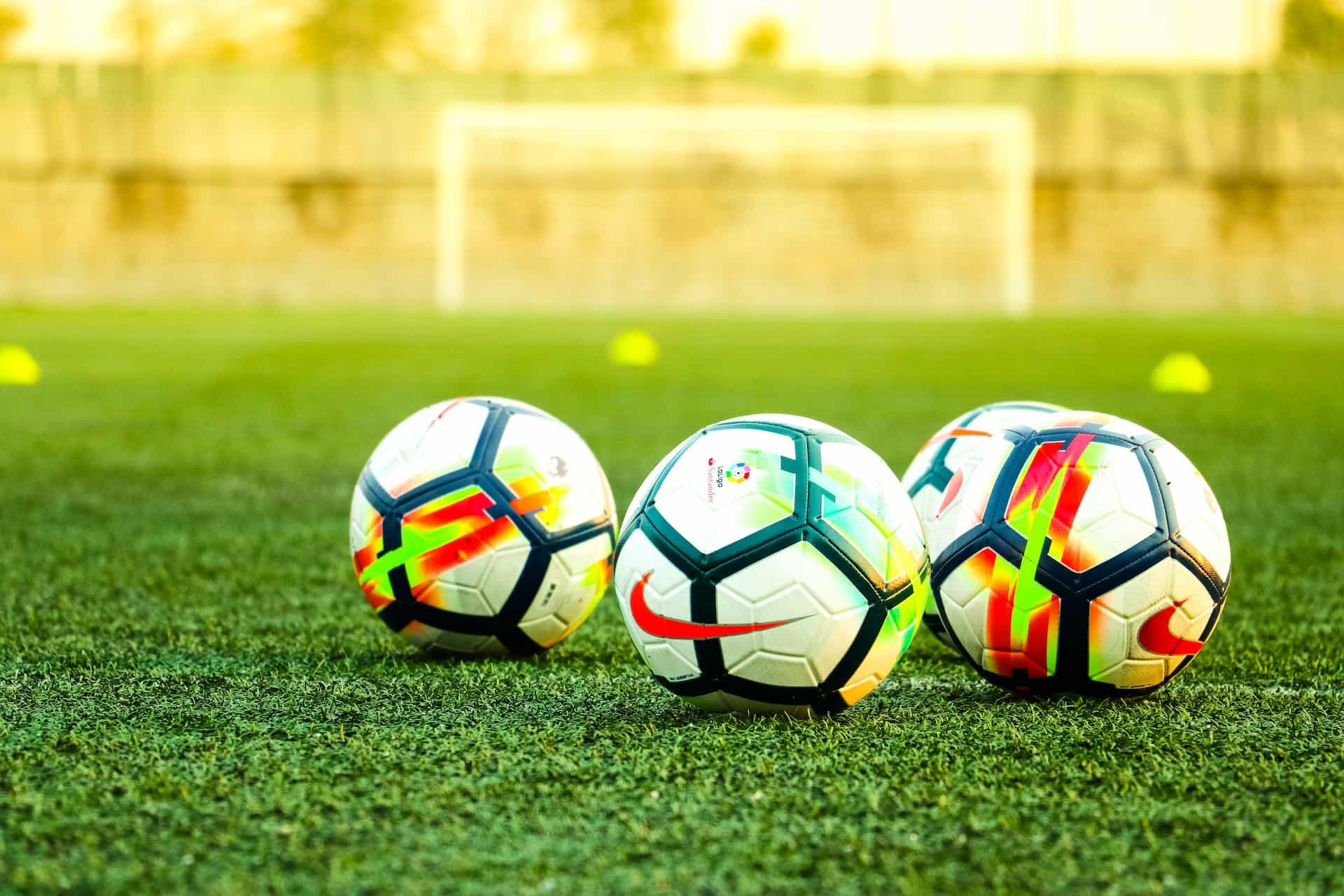 Three soccer balls sit on a field.