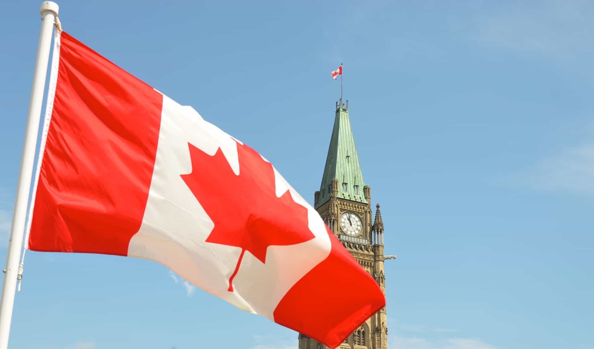 The iconic Canadian flag, with its red and white flowers and Maple Leaf, rustling in the wind in front of the Canadian parliament in the capital city of Ottawa in the province of Ontario.