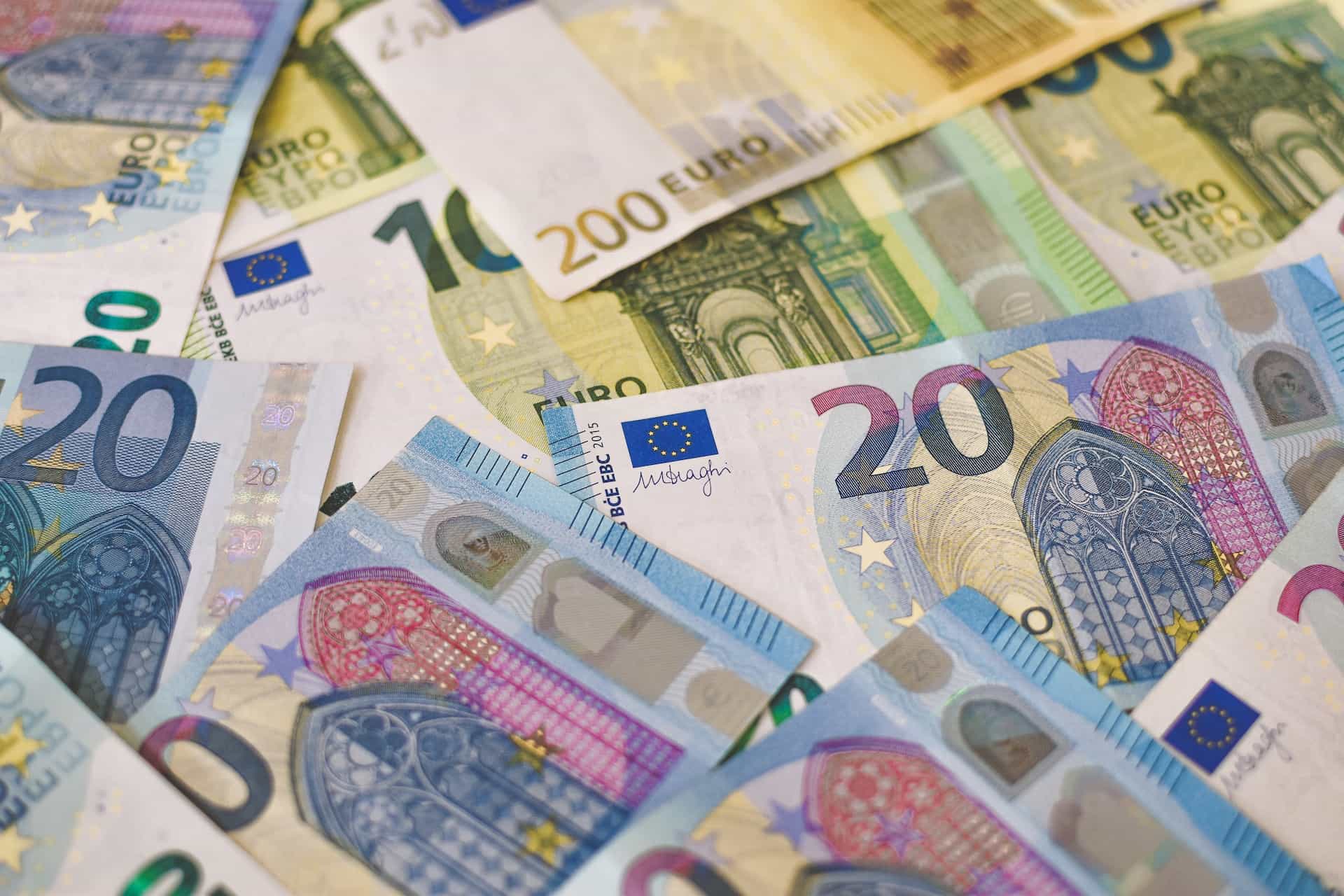 Many Euro bills are spread out on a flat surface.
