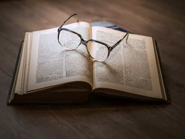 Eyeglasses sit on an open leather-bound book.