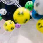 Multi-colored lottery balls fly around a barrel.