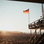 A black, red, and yellow flag on a structure at a beach.