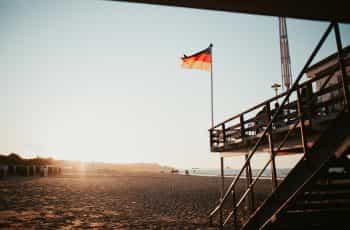 A black, red, and yellow flag on a structure at a beach.