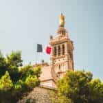 A flag hoisted on a church with a statue on it.