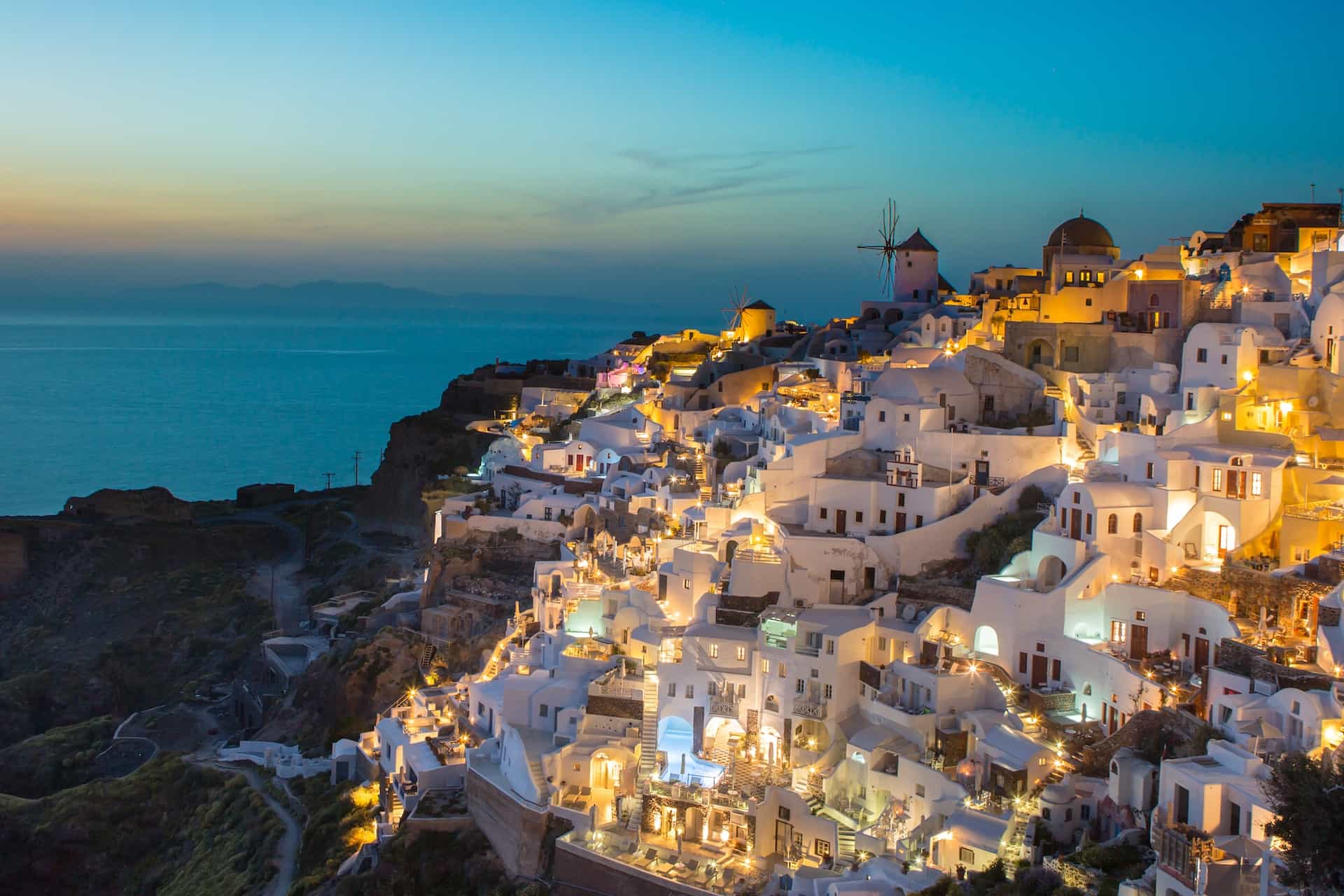 White and brown houses on a hilly terrain near sea after sunset.