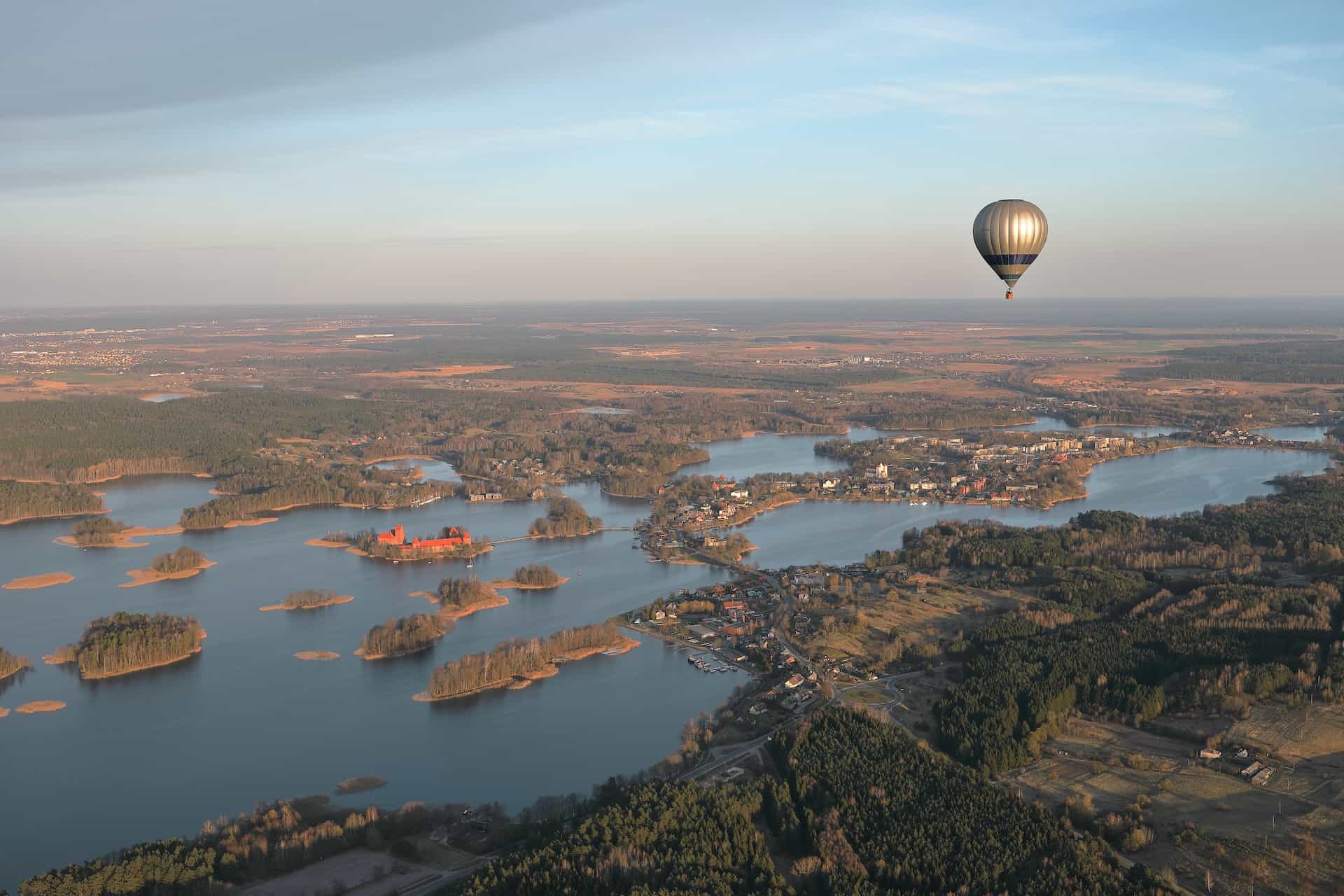 A hot air balloon hovering over parts of land and water.