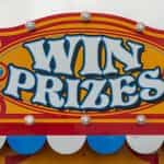 A carnival sign reads WIN PRIZES in yellow and red paint.