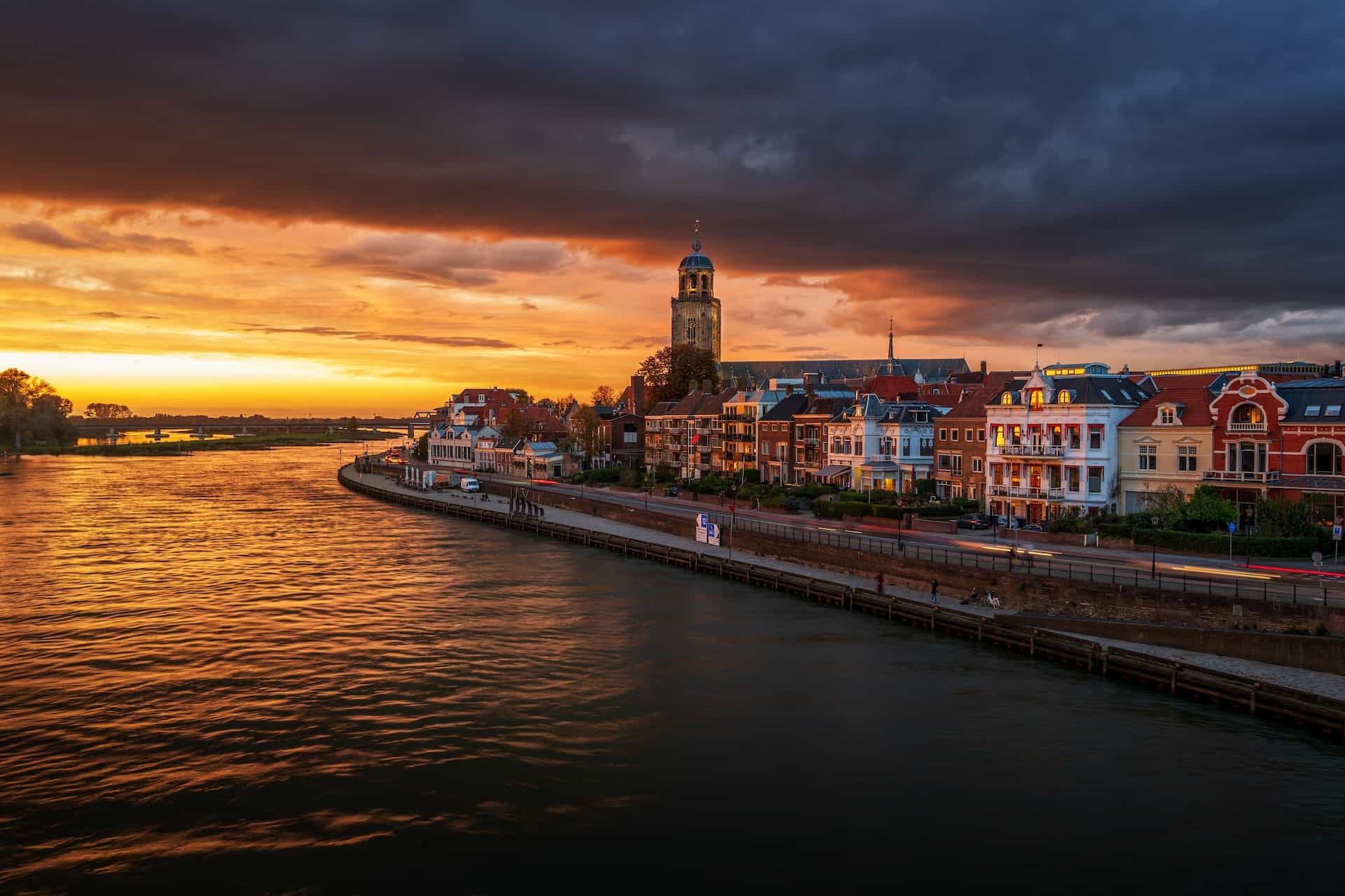 A city with buildings near a river under an orange sky.