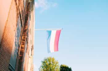 A red, white, and blue flag hoisted out of a window.