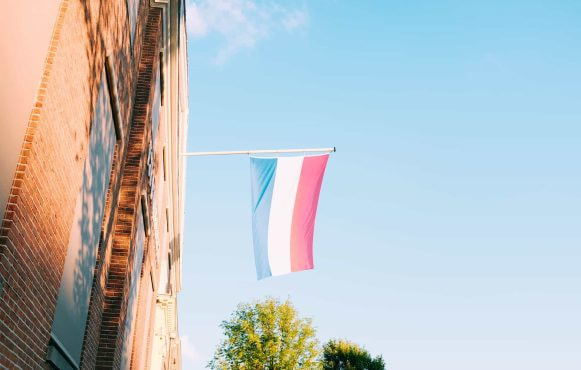 A red, white, and blue flag hoisted out of a window.