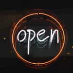 A classic open sign in neon lettering in the window of a shop or restaurant.