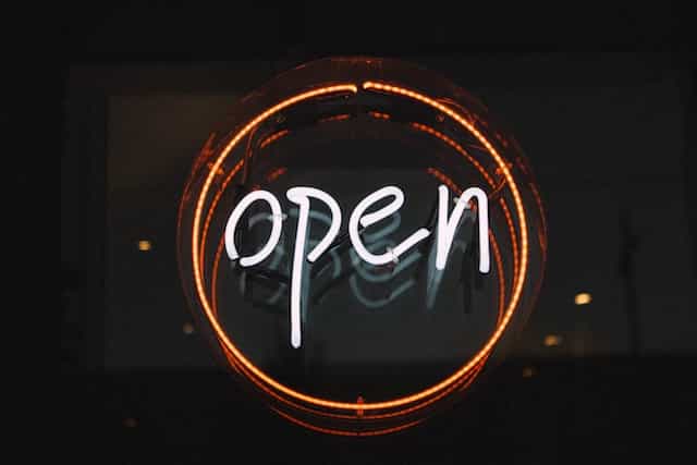 A classic open sign in neon lettering in the window of a shop or restaurant.