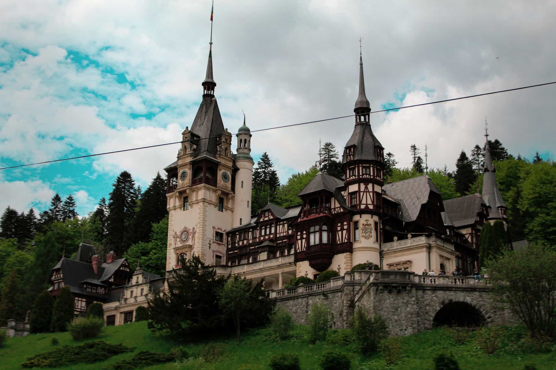 A brown and black castle atop a lush grass-covered hill.