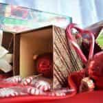 Overflowing gold gift boxes, candy canes, and red ornaments piled together on a red blanket.