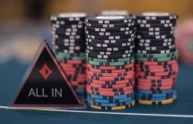 Chips and an ‘All IN’ dealer button on a poker table.