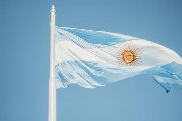 The Argentina flag flies against a blue sky.