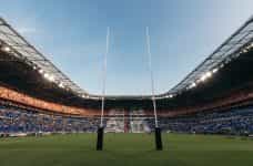 Two rugby goal posts in a large stadium.