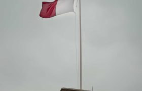 A red and white flag against a cloud sky.