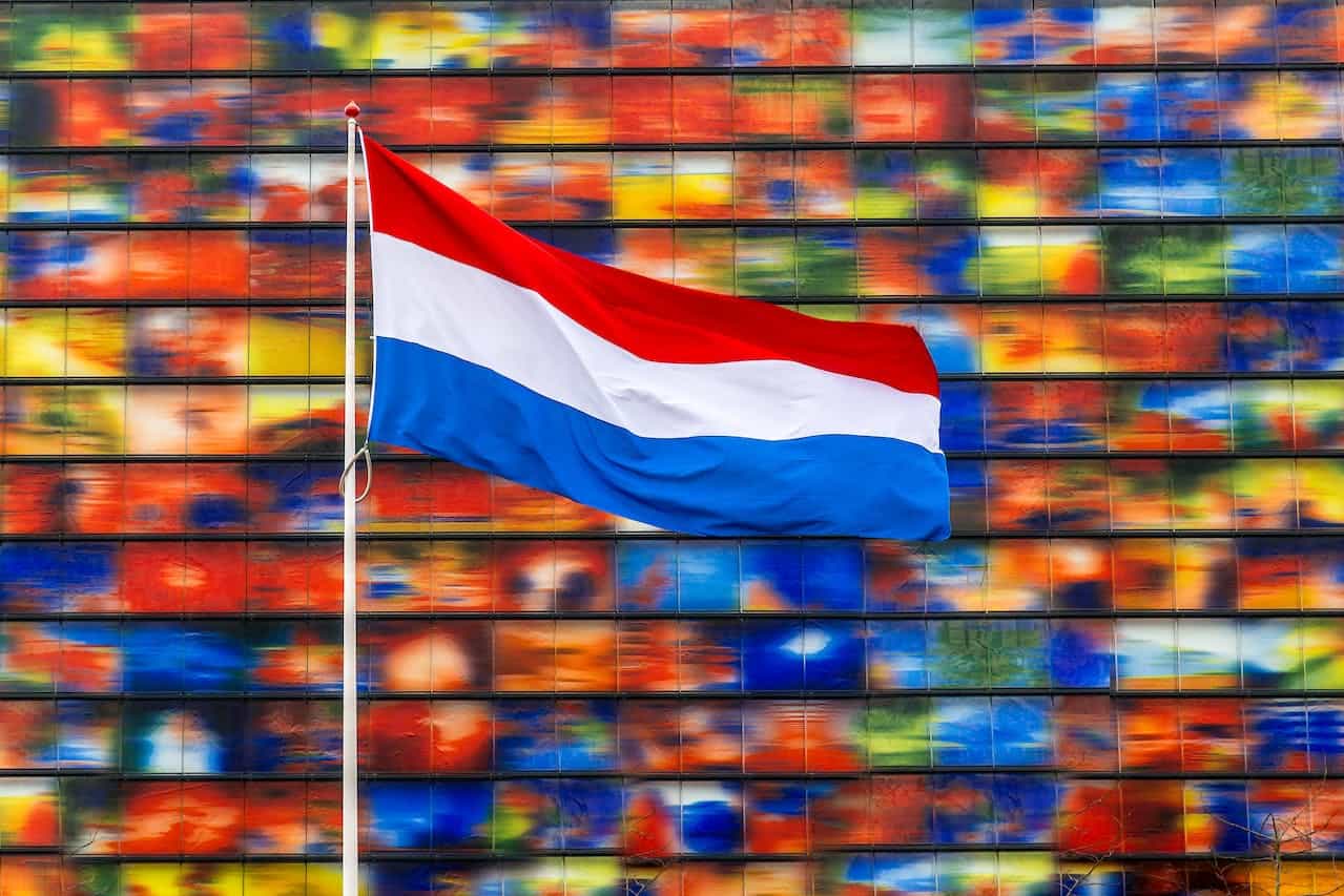 A red, white, and blue flag in front of a colourful background.